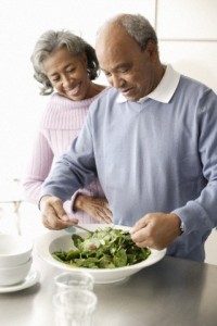 Senior couple tossing salad in kitchen
