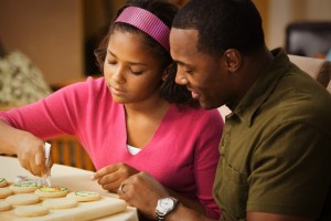 Father and daughter decorating Christmas cookies