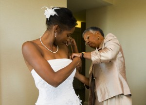 African American mother helping bride with wedding dress