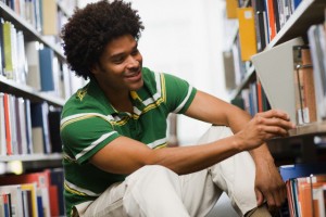 College Student Removing Book From Library Shelf