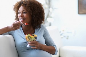 Pregnant Woman Eating Fruit Salad on Sofa