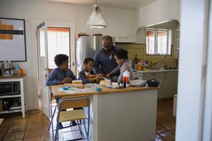 Father and children baking cake in kitchen