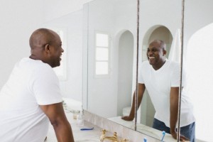 Man looking in bathroom mirror, smiling
