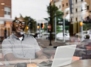 Black man using laptop in coffee shop