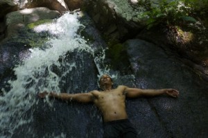 Black man in waterfall large rock wall